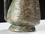 a vase that has a handle on it on a table