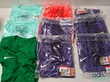 de nombreux t-shirts de différentes couleurs, rangés dans des sacs en plastique posés sur une table