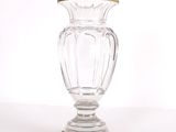un vase en verre transparent à bord doré, posé sur un socle en bois