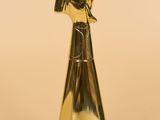 gold metal sculpture of a hand holding a flower on a beige background