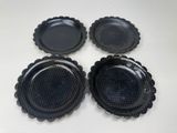 quatre assiettes en plastique noir posées sur une table blanche, sur fond blanc