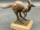 bronze statue of a kangaroo on a marble base on a gray background