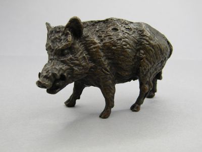 une petite statue représentant un sanglier debout sur une surface blanche