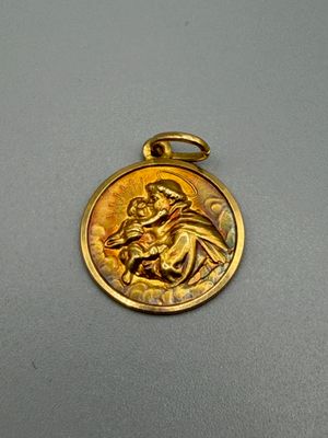 un gros plan d'une médaille d'or sur laquelle figure une image de Jésus