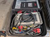 une image représentant une mallette à outils remplie de matériel électrique, posée à même le sol
