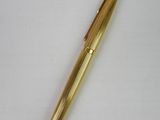 a gold colored pen sitting on top of a white surface