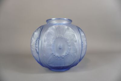 un vase en verre bleu posé sur une surface blanche