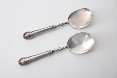 pair of silver spoons on a white surface with a white background