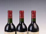 three bottles of red wine sitting on top of a table