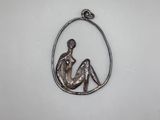 un pendentif en argent représentant une femme assise au sein d'un cercle