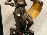 statue en bronze représentant une femme tenant un livre posé sur une table