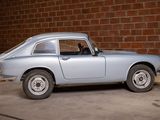 a silver car that is parked in front of a brick wall