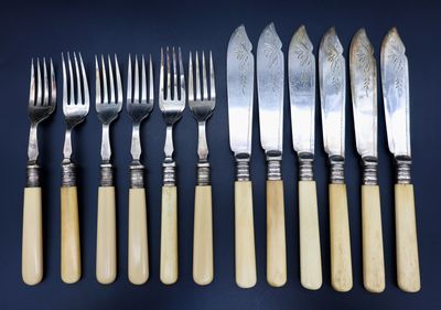 six fourchettes et cinq couteaux sont alignés sur une table