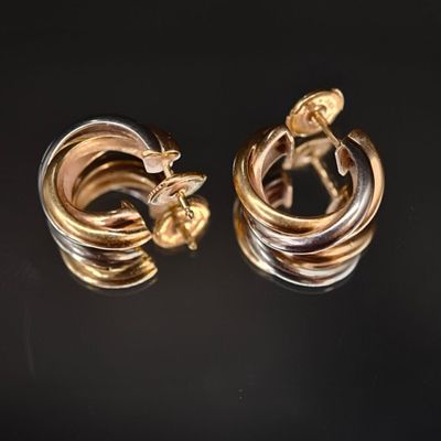 deux boucles d'oreilles en forme d'anneaux, l'une en or et l'autre en argent, sur un fond noir
