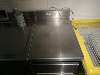 un plan de travail en inox avec une poubelle jaune en arrière-plan
