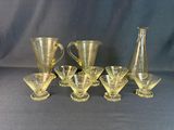 six glass vases and a pitcher sitting next to each other on a table