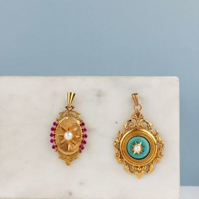 deux pendentifs en or et en turquoise posés sur une dalle de marbre