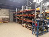 L'entrepôt est rempli de nombreuses étagères et de palettes.