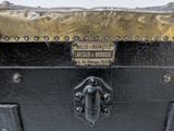 a black trunk with a brass handle and a sign on it
