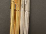 three different types of pens are lined up on a black surface
