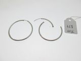une paire de boucles d'oreilles créoles en argent posées sur une surface blanche, avec une étiquette de prix
