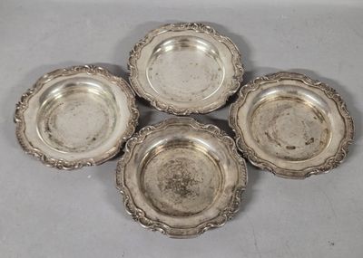 four silverplated dishes are arranged on a white surface