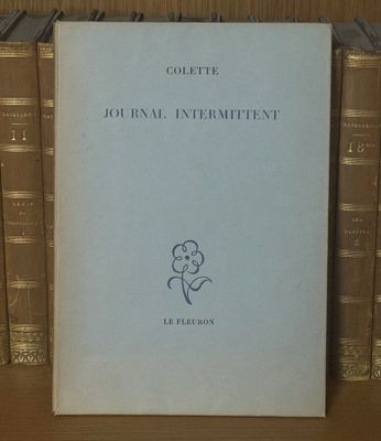 un livre posé sur une étagère, devant une pile de livres