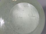 a green vase with writing on it sitting on a table