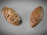 deux boutons en bois sculptés, ornés de motifs, posés sur une table