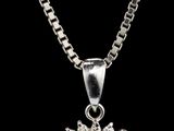 un pendentif en émeraude et diamants, suspendu à une chaîne, sur fond noir