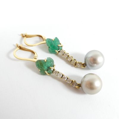 une paire de boucles d'oreilles en perles vertes et blanches et en or, posées sur un fond blanc