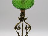 une lampe ancienne en verre vert avec un pied en métal, sur fond blanc