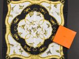 a black and white scarf with a gold border and a orange box