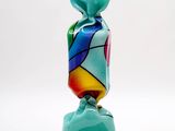 brightly colored glass vase on a black stand against a white background