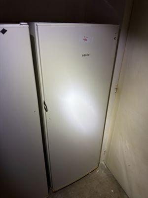 un réfrigérateur blanc dans un coin d'une pièce sombre