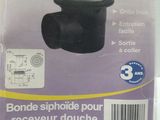 packaging of a black toilet drain with a white lid on a white table