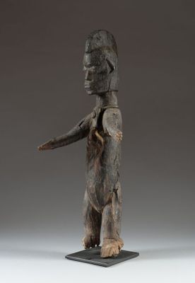 une statue en bois représentant un homme tenant un couteau dans la main droite