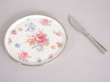a plate with a rose pattern on it next to a knife and fork