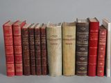 several old books are lined up in a row on a gray surface