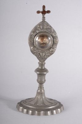 une horloge en argent posée sur un socle surmonté d'une croix