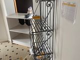 une étagère en métal sur laquelle est posée une horloge, dans une pièce