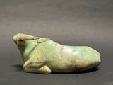 a green sculpture of a cow laying down on the ground