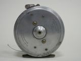 a silver fishing reel that is on a white surface