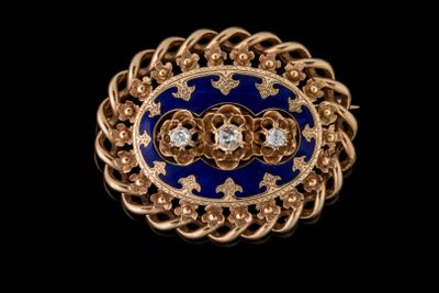 un gros plan sur une broche bleue et dorée sertie de diamants