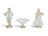 trois figurines en verre représentant une femme et un homme sur fond blanc