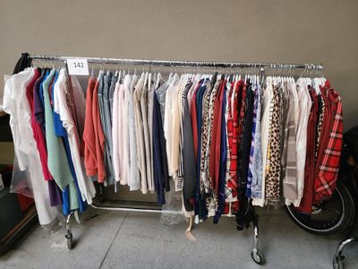 beaucoup de vêtements suspendus à une étagère dans une pièce