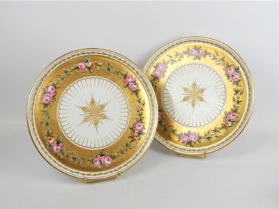 deux assiettes ornées de fleurs dorées et roses sur un fond blanc