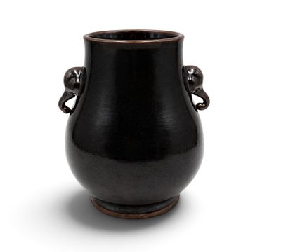 a black vase with two handles sitting on a white surface