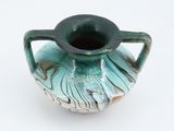 a blue and green vase with a handle on a white surface