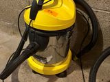 un aspirateur jaune et noir posé par terre près d'un mur